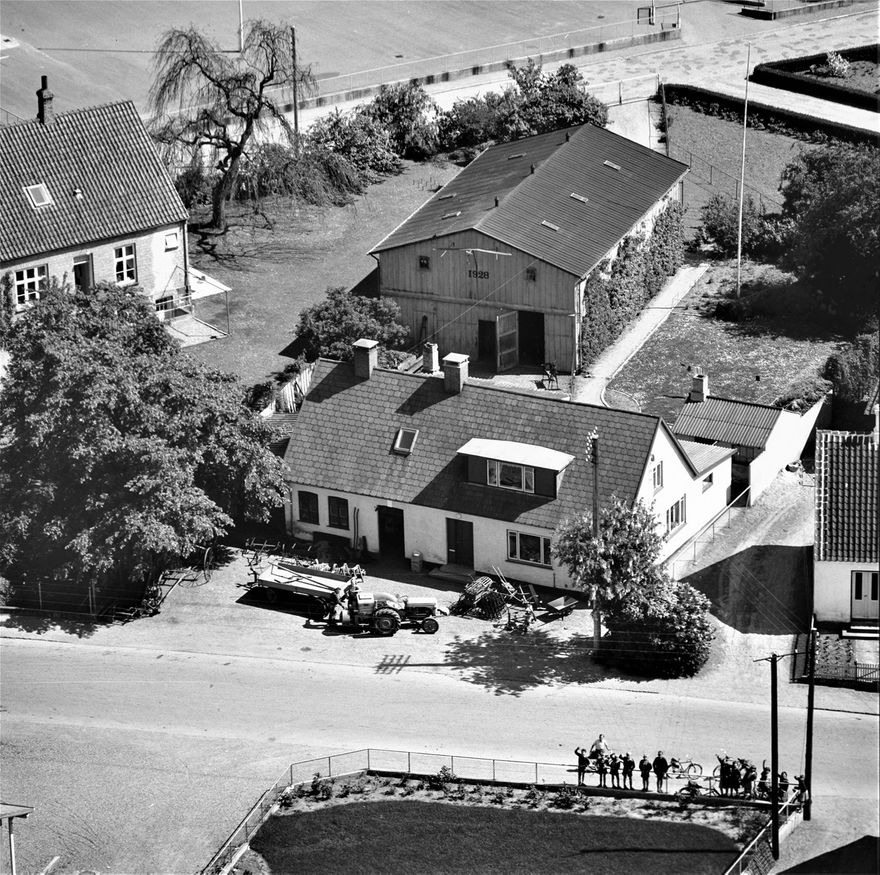 Luftfoto af Ørslev Smede og Maskinværksted 1959. Det skulle efter forelagte oplysninger være Smed Christen Nielsen og Mogens Eiberg der står ved traktoren på forpladsen foran smedien.